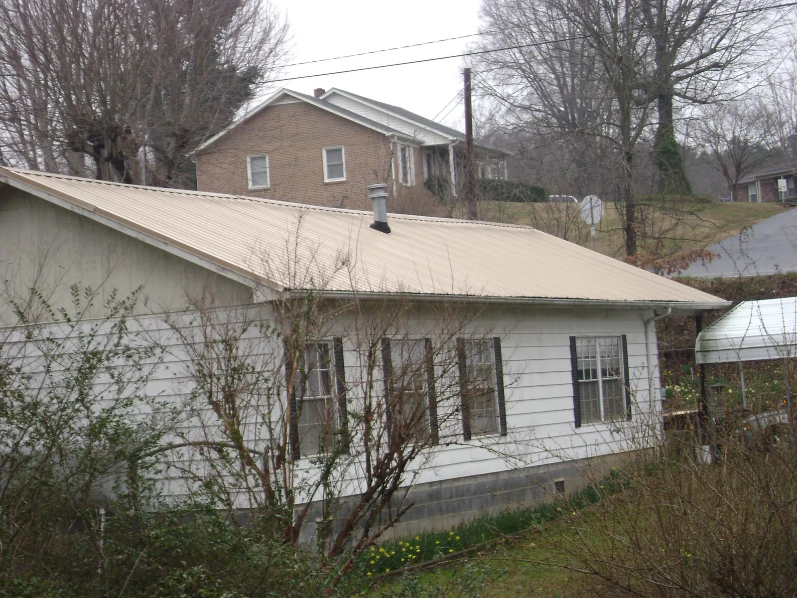 Tan metal roof on a white sided house set into a hillside — Commercial Roofing by Roofing Brothers in Moscow